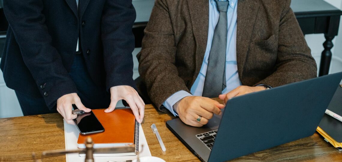 crop colleagues gathering at table with laptop in office